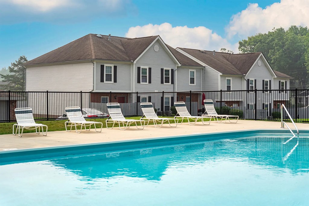 A pool in front of a house with a fence around it.
