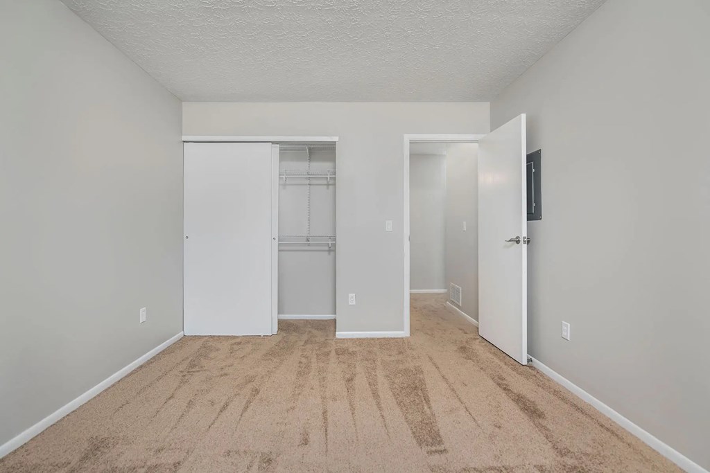 A room with a carpeted floor and a white door.