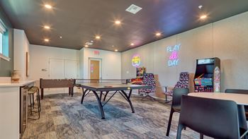 A room with a ping pong table and chairs.
