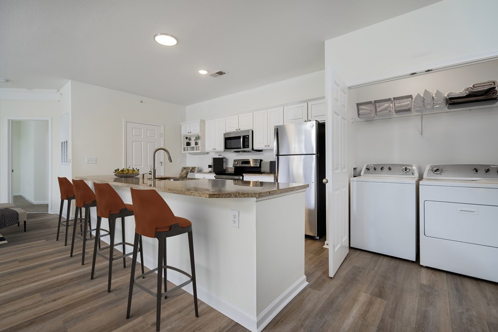 A kitchen with white appliances and brown bar stools.at Arlington Park, Hilliard, 43026