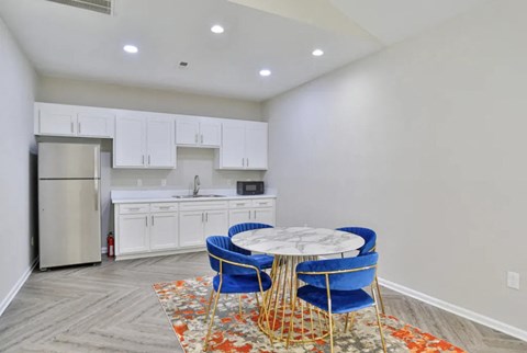 a kitchen with white cabinets and a table with blue chairs