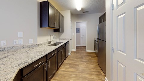 A kitchen with dark brown cabinets and a granite countertop.