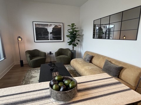 A living room with a couch, chair, and a bowl of fruit on the coffee table.