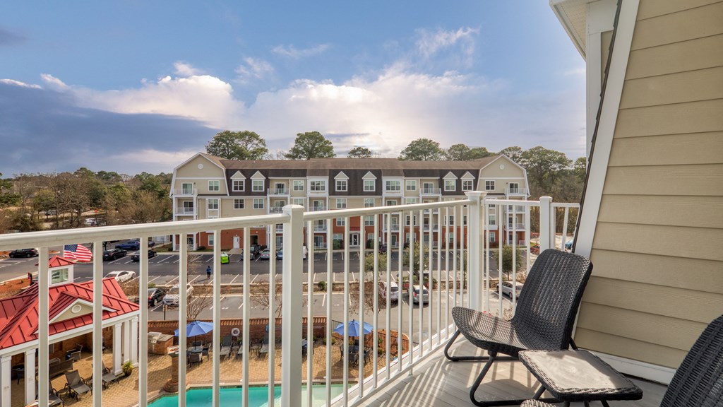 a balcony with two chairs and a pool and some buildings