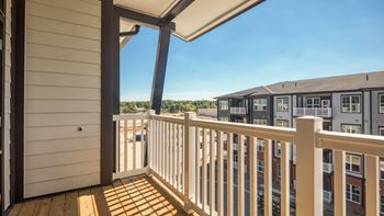A balcony with a white railing and a view of other buildings.