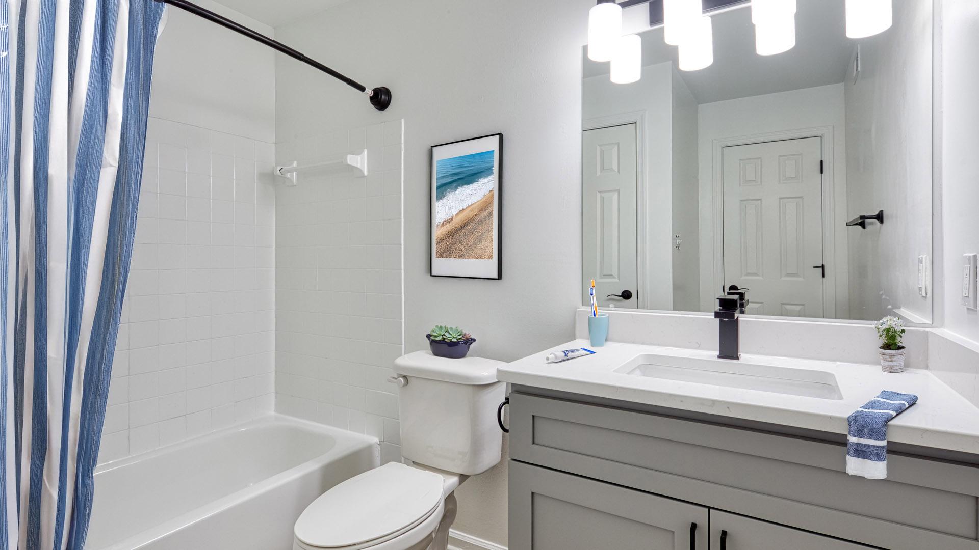 A bathroom with a white toilet, sink, and a blue shower curtain.