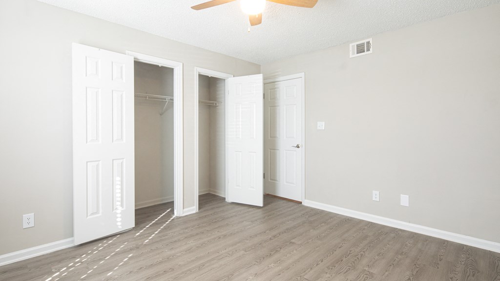 an empty living room with three closets and a ceiling fan
