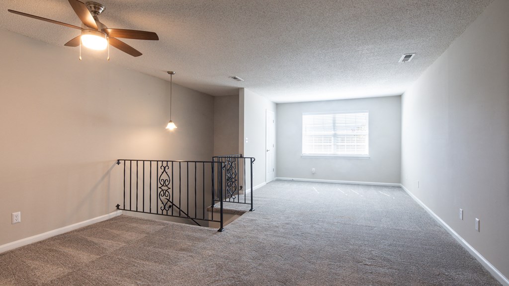 an empty living room with a ceiling fan and a window