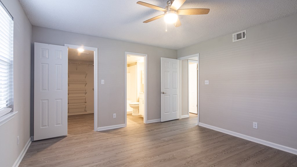 an empty living room with wood floors and a ceiling fan
