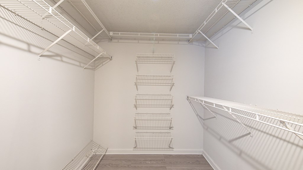 a room with white walls and a white closet with metal shelves