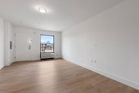 A large empty room with a view of a building outside the window.