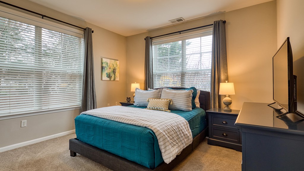 an empty bedroom with a bed and two windows