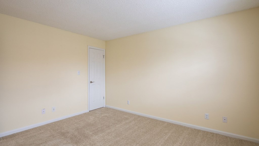 A room with a white door and beige walls.
