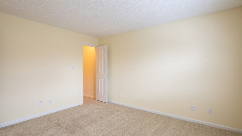A room with a carpeted floor and a white door.