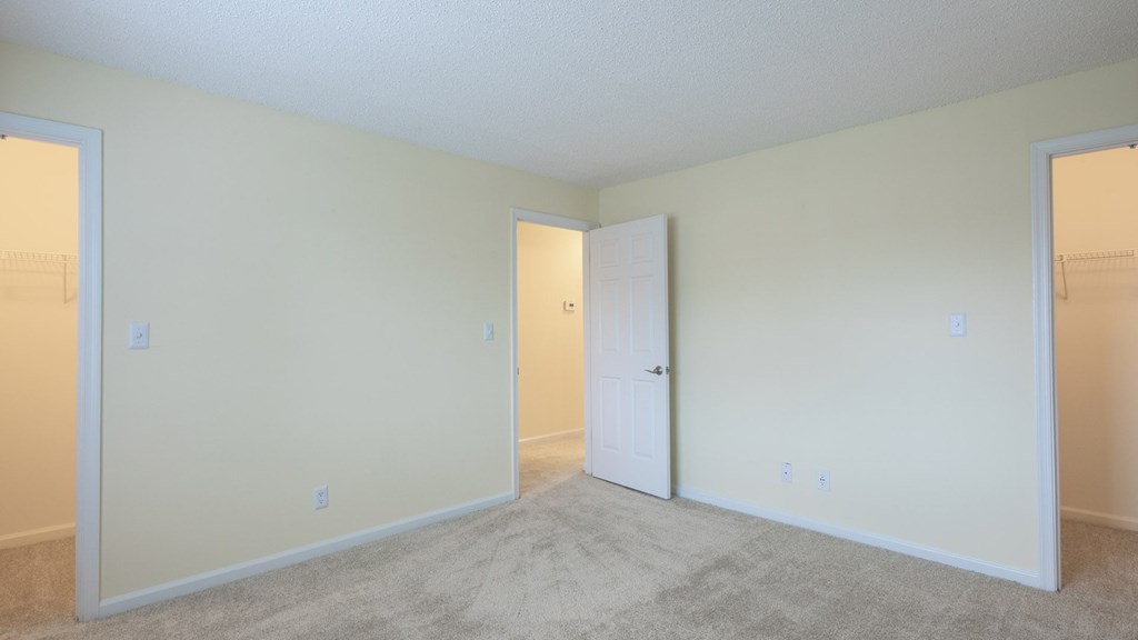 A room with a carpeted floor and two white doors.