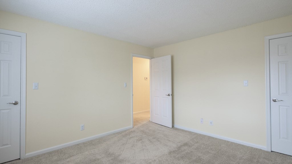 A room with two doors and carpeted floor.
