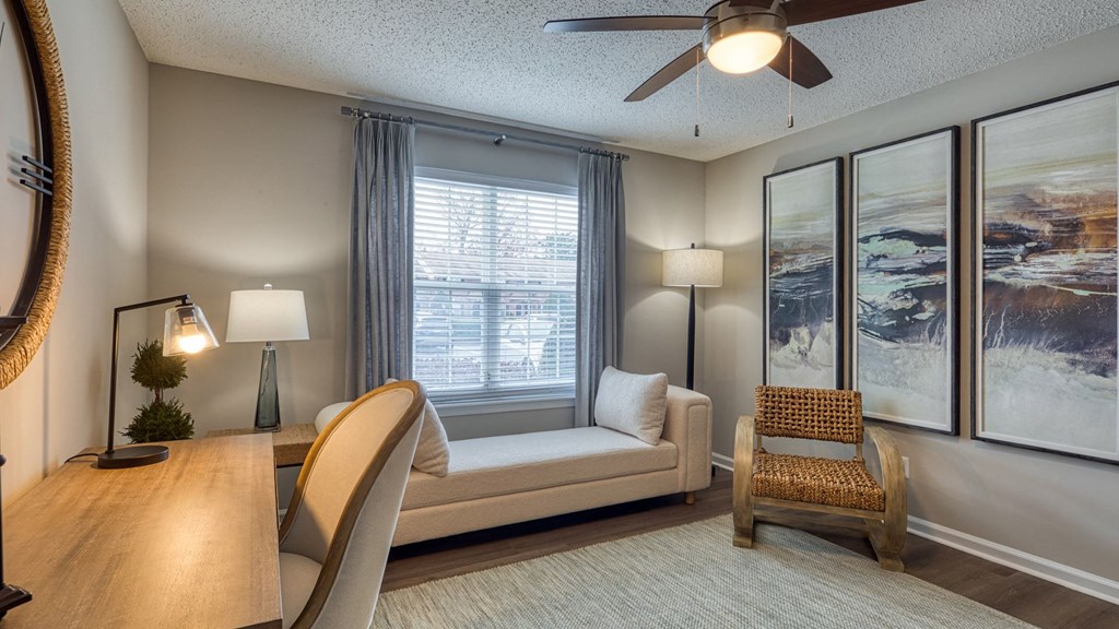 A living room with a couch, a chair, a table, and a ceiling fan.