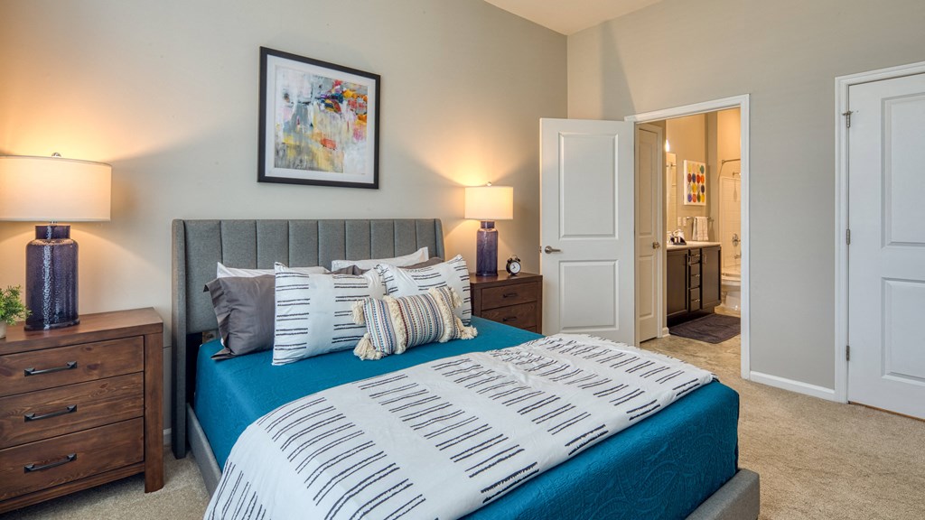 a bedroom with a bed with a blue blanket and pillows