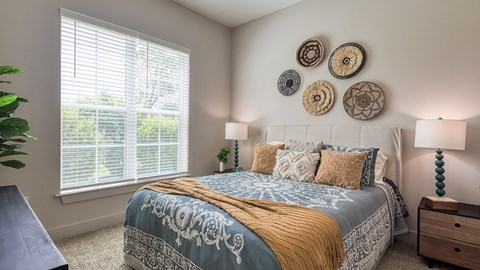 A bedroom with a bed, two lamps, and decorative wall plates.
