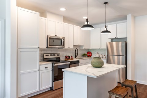 A kitchen with white cabinets and a stainless steel refrigerator.
