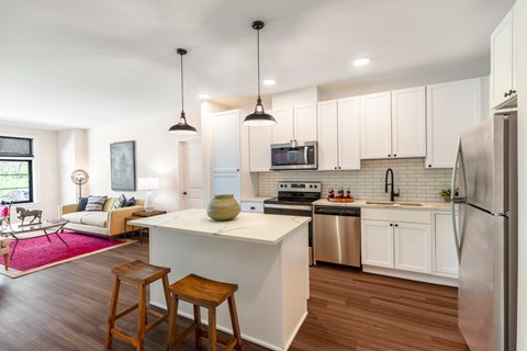 A kitchen with white cabinets and a white island with a sink.
