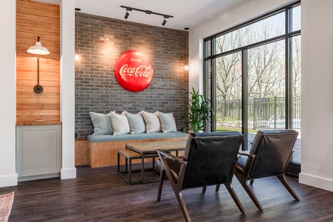 A Coca-Cola sign is mounted on a brick wall above a bench.