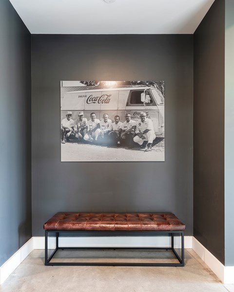 A Coca-Cola advertisement is hanging on a wall above a bench.
