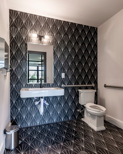A bathroom with a black and white patterned wallpaper.