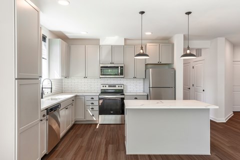 A modern kitchen with a white island and stainless steel appliances.