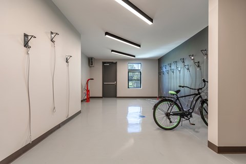 A bike is leaning against a wall in a spacious room with white walls and a white floor.