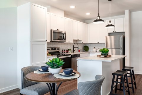 A modern kitchen with a dining table set for two.