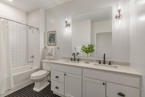 A white bathroom with a toilet, sink, and a mirror.