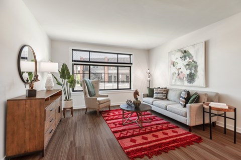 A living room with a red rug and a white couch.