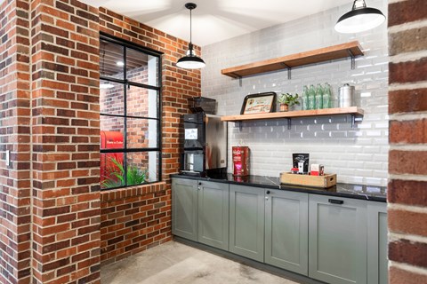 A kitchen with a brick wall and grey cabinets.