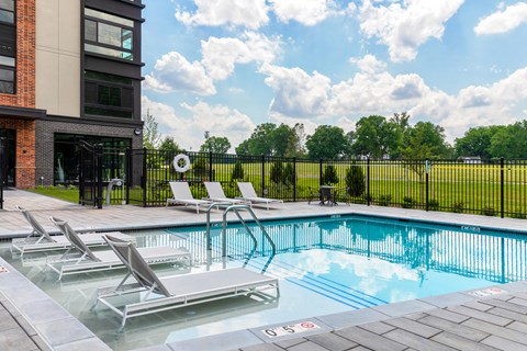 A pool with lounge chairs and a building in the background.