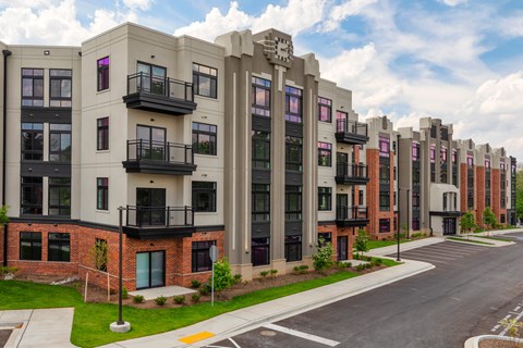 A row of modern apartment buildings with balconies and a clock on the front of one.