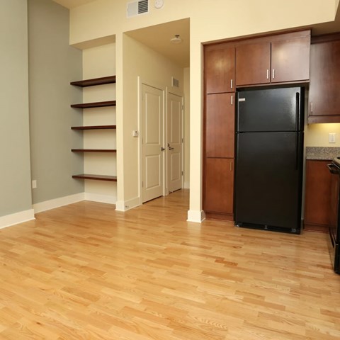 A black refrigerator sits in a kitchen next to a wooden cabinet.