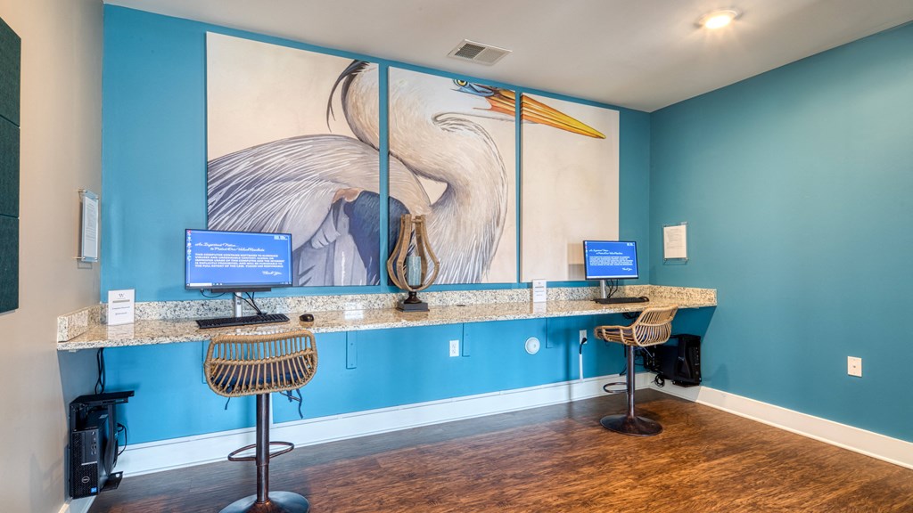 a reception area with two computers and a large painting on the wall