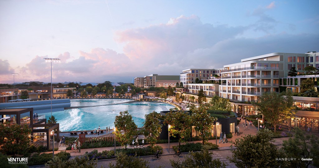 A modern building complex with a pool in the foreground and a sunset sky in the background.