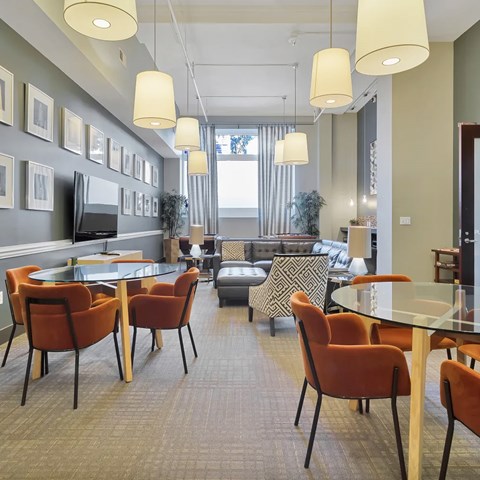 A modern dining room with a glass table and orange chairs.