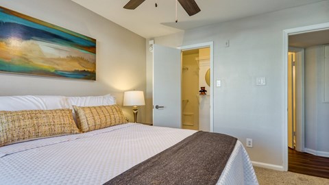 A bedroom with a large bed and a painting on the wall.