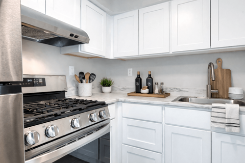 A modern kitchen with a stainless steel stove and white cabinets.