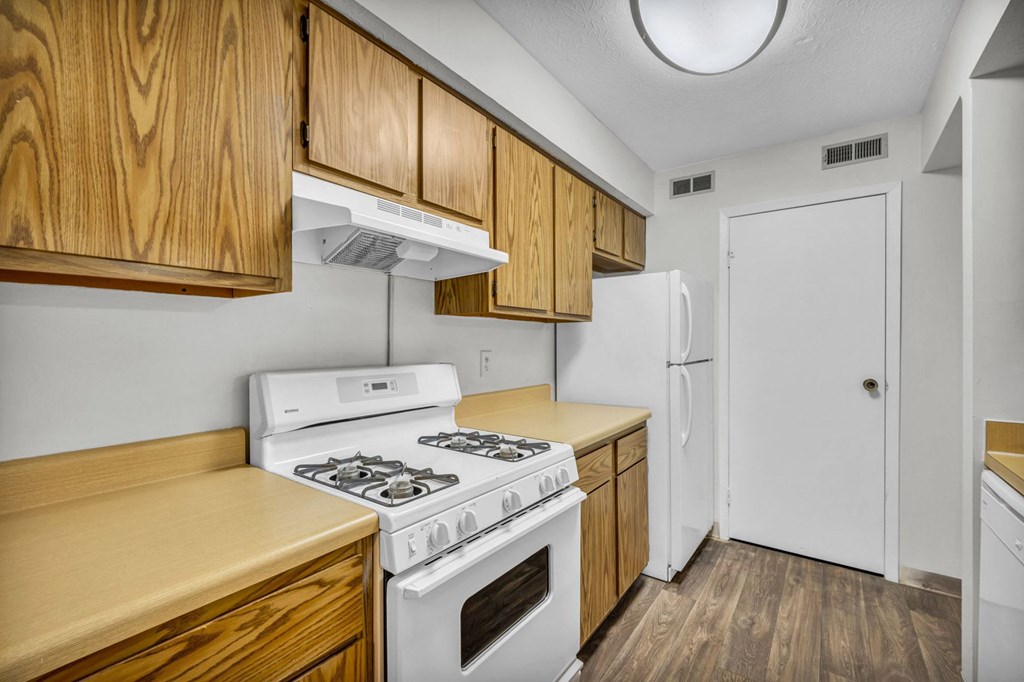 A kitchen with a white stove and wooden cabinets.