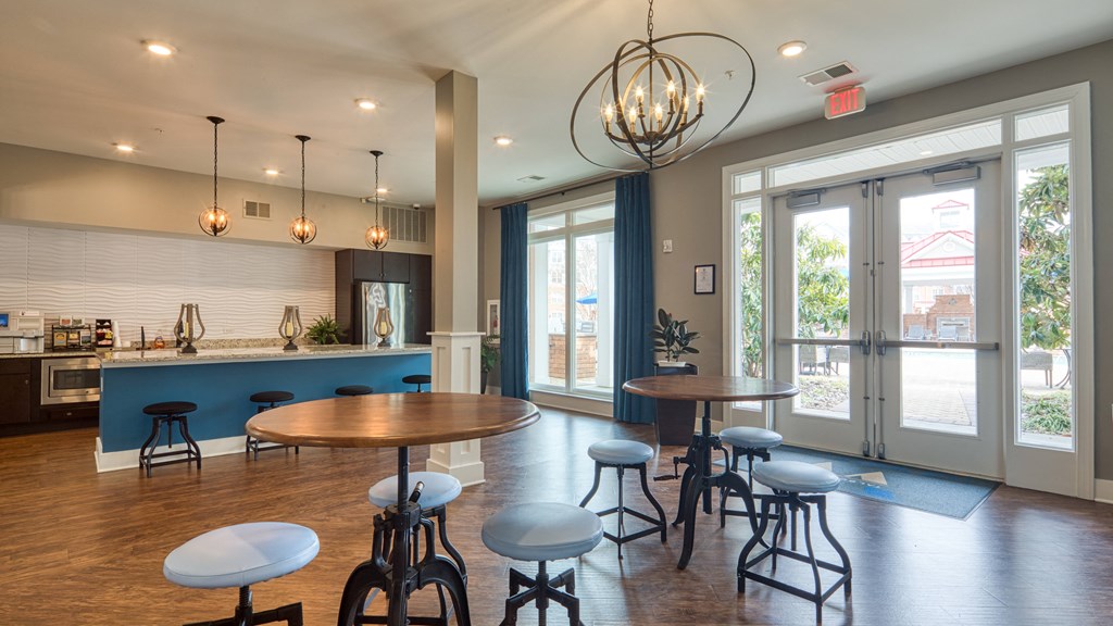 a dining room with tables and chairs and a kitchen with large windows