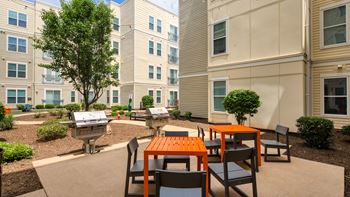 an outdoor patio area with tables and chairs at an apartment building at Proximity at ODU, Norfolk, Virginia