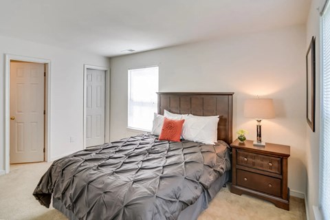 A bedroom with a large bed and a nightstand with a lamp.
