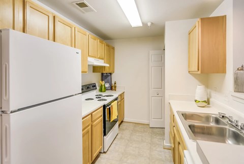 A kitchen with a white refrigerator and wooden cabinets.