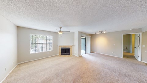 A spacious living room with a fireplace and a ceiling fan.