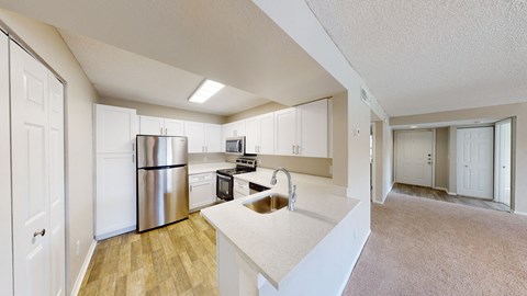 A kitchen with white cabinets and a stainless steel refrigerator.