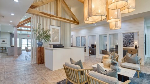A living room with a white reception desk and a white sofa with grey cushions.